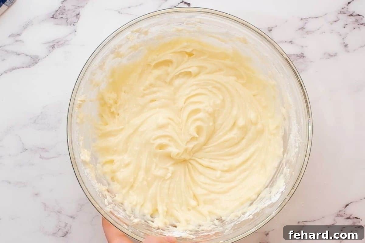 Pumpkin Roll Recipe with Cream Cheese Filling A mixing bowl filled with luscious, smooth cream cheese filling, whipped to a perfect creamy consistency, ready for the pumpkin roll.