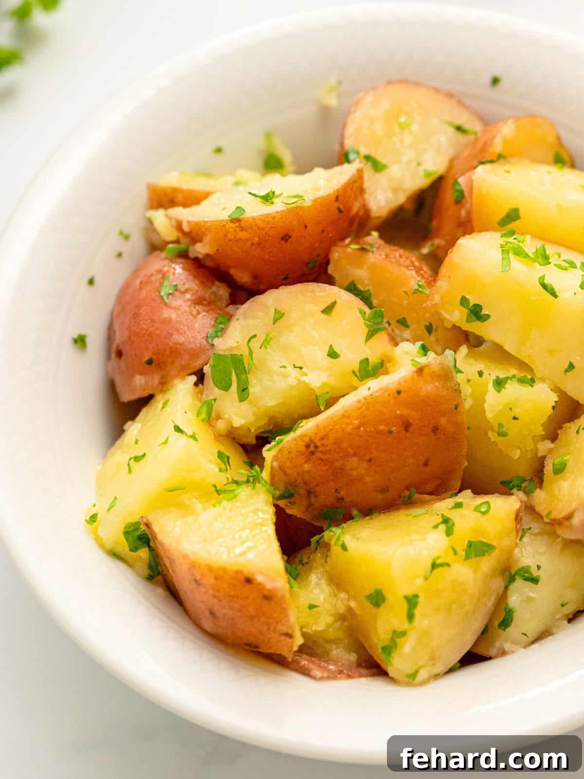 A rustic bowl filled with perfectly buttered red potatoes, generously tossed with vibrant fresh parsley, ready to be served as a delicious side dish.