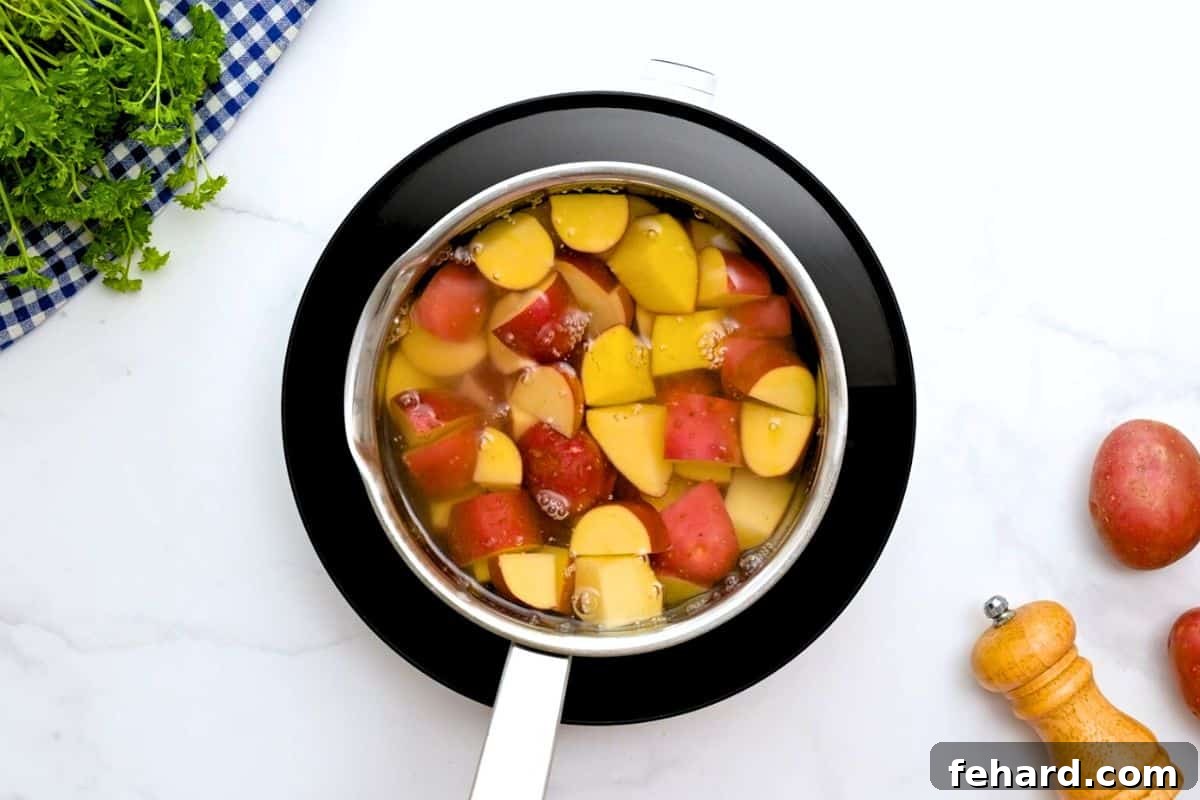 Diced red potatoes submerged in cold, salted water in a medium saucepan, illustrating the crucial first step of the cooking process.