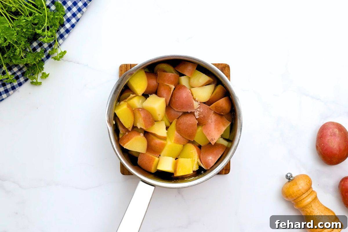 Perfectly boiled and drained quartered red potatoes resting in a medium saucepan, after being returned to the pot to steam dry, showcasing their tender texture.