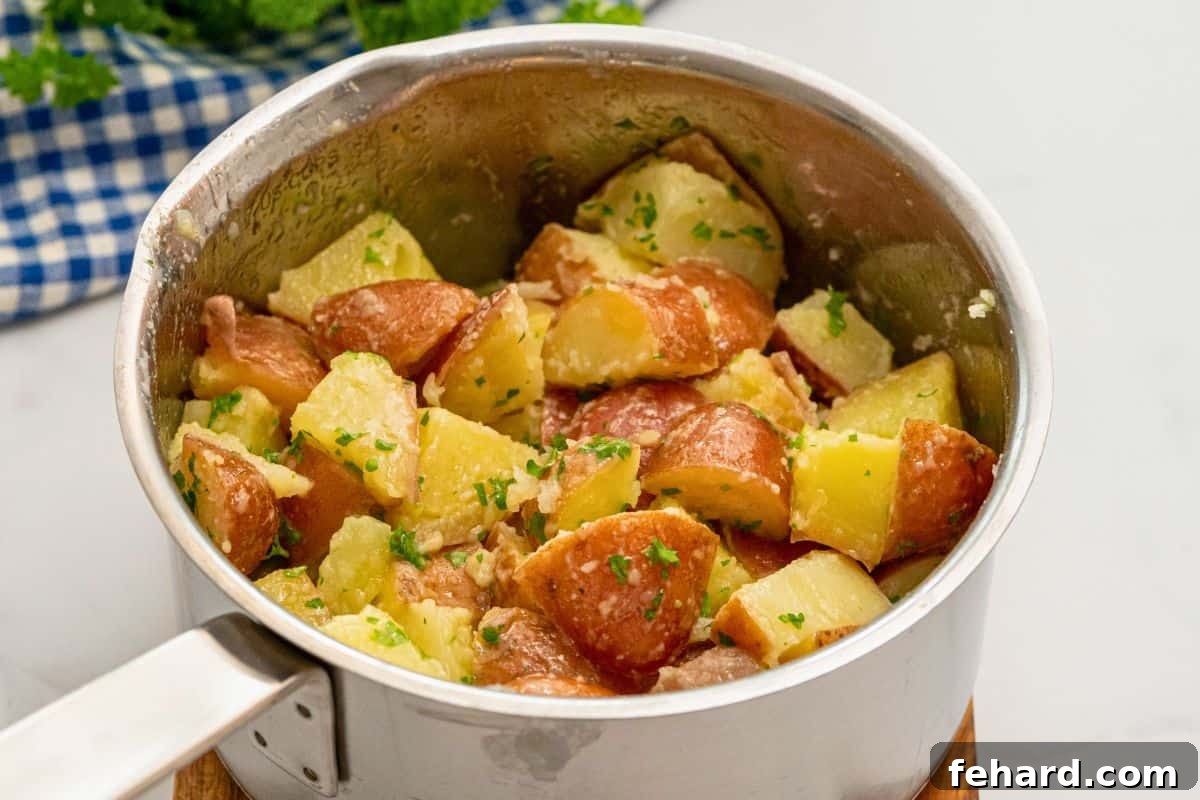 Vibrant red boiled potatoes, glistening with melted butter and generously flecked with fresh green parsley, gently tossed in a medium saucepan.