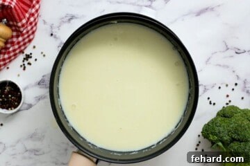 Cream sauce next to fresh broccoli and cooked rice.