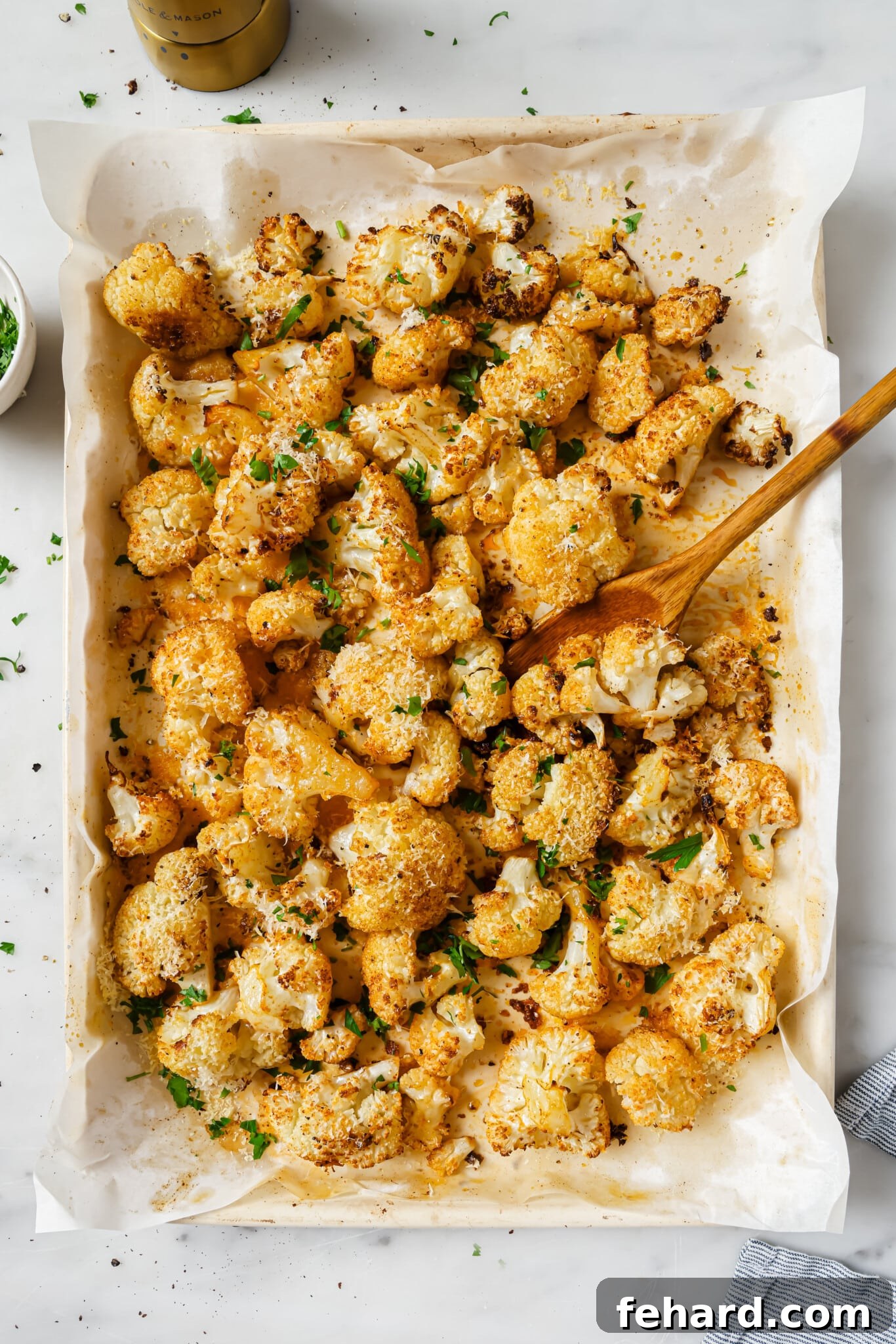 Close up of cauliflower on a baking sheet with parsley as garnish. 