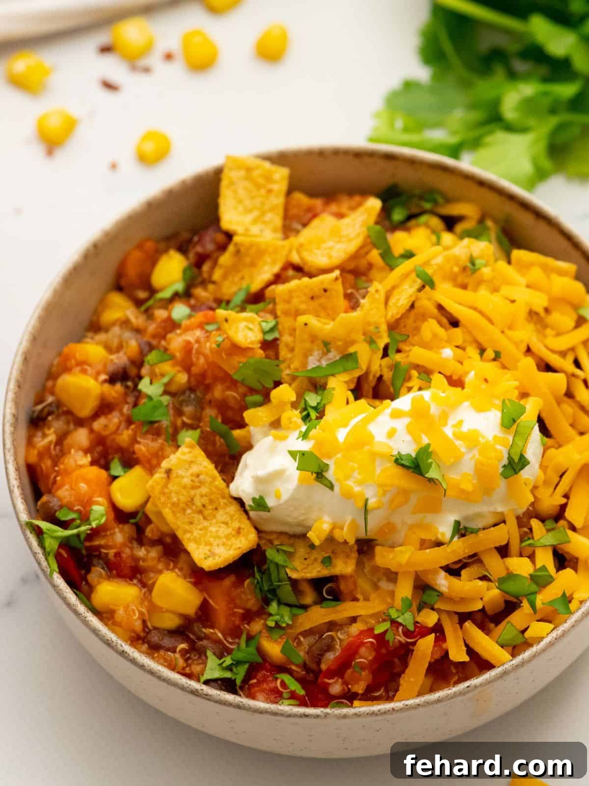 A vibrant bowl of Instant Pot Sweet Potato Chili, richly colored and topped with creamy sour cream and crunchy corn chips, showcasing its hearty and appetizing appeal.
