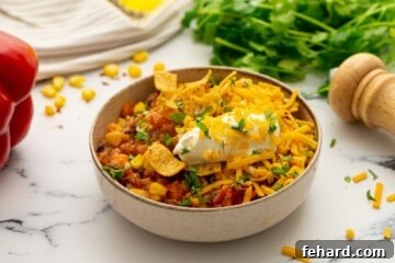 Bowl of sweet potato quinoa chili topped with sour cream and corn chips.