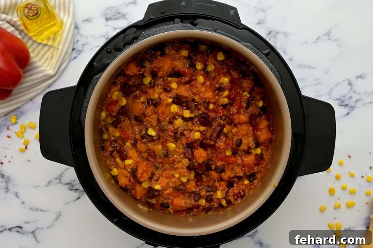 A top-down view of the perfectly cooked Instant Pot Sweet Potato Chili, still steaming gently inside the inner pot, ready to be served and garnished with fresh toppings.