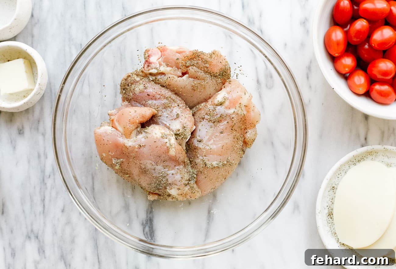 Close-up of chicken thighs in a bowl, generously seasoned with herbs and spices, ready for cooking.