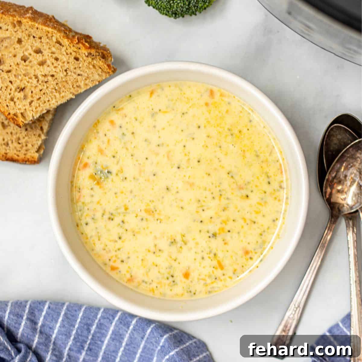 A warm bowl of Instant Pot Broccoli Cheddar Soup, rich and creamy, served next to crusty gluten-free bread, with an Instant Pot in the background.