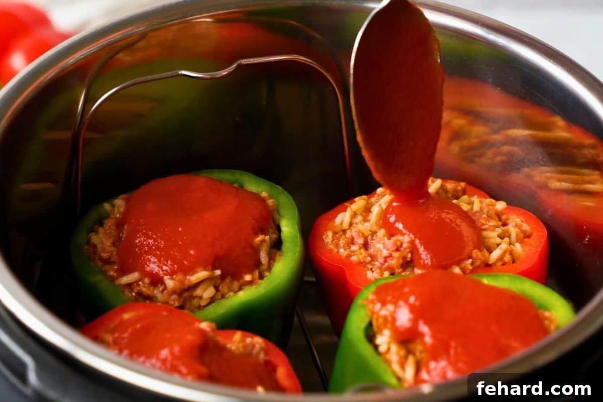 Adding Tomato Sauce to Stuffed Peppers in Instant Pot A spoon gently pouring extra tomato sauce over four stuffed bell peppers, carefully arranged on a trivet inside an Instant Pot, prior to cooking.