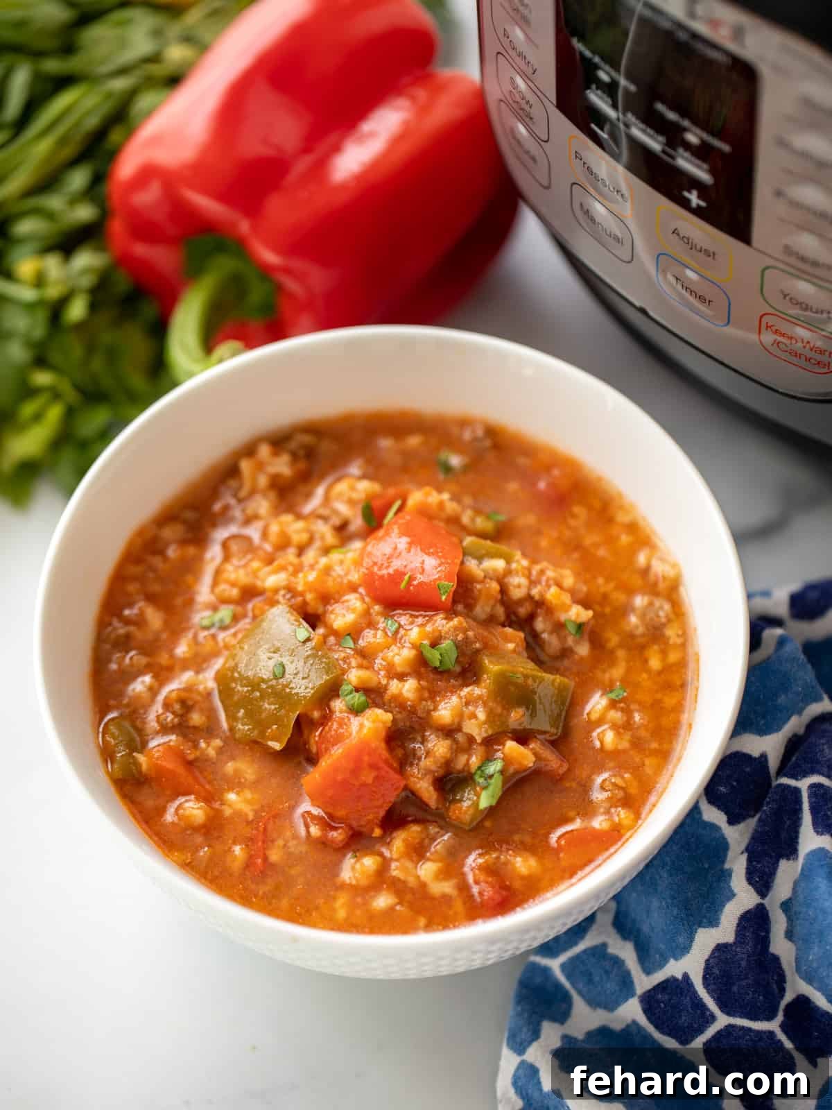 A steaming bowl of Instant Pot Stuffed Pepper Soup, garnished with fresh herbs, sits beside an Instant Pot pressure cooker and vibrant bell peppers. This image captures the hearty and appealing nature of the dish.