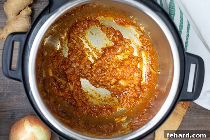Pressure Cooker Butter Chicken Spices and tomato paste being toasted in melted butter in an Instant Pot inner pot.