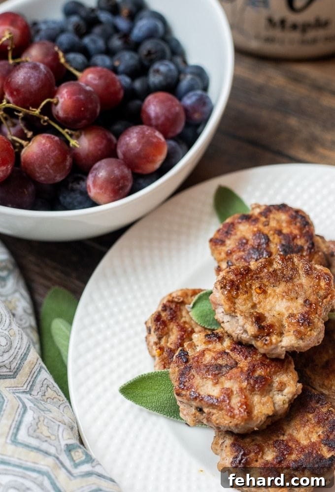 Homemade Breakfast Sausage Recipe A plate of golden-brown homemade breakfast sausage patties alongside fresh, colorful fruit, ready for a healthy and delicious breakfast.