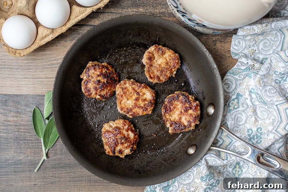 Homemade Breakfast Sausage Patties Cooking Golden-brown homemade sausage patties sizzling in a nonstick skillet, ready to be flipped.