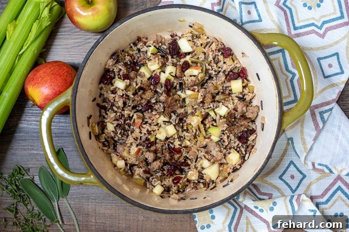 Hearty wild rice stuffing with sausage, apples, and cranberries in a rustic Dutch oven, ready to fill the squash.