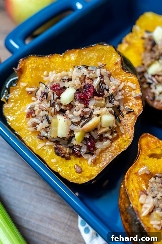 Two beautifully stuffed acorn squash halves baking in a dish, showing off their rich golden color and abundant filling.