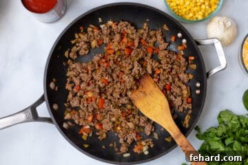 Ground beef sauteed with onion pepper in skillet.