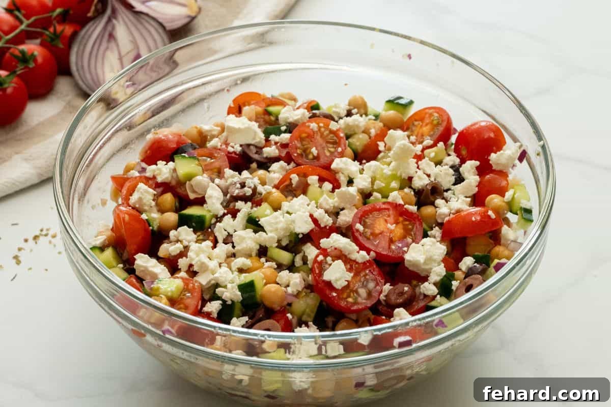 Finished Chickpea Salad Recipe A large bowl of Mediterranean Chickpea Salad with chickpeas, olives, cucumbers, tomatoes, and red onions, generously topped with crumbled feta cheese.
