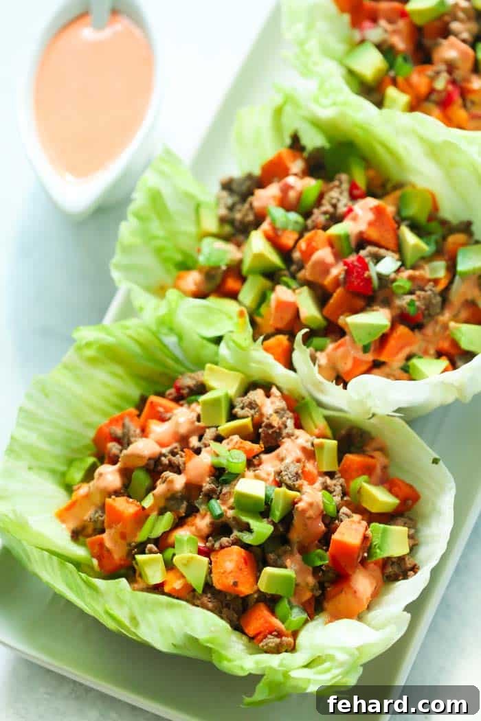 A close-up shot of two Ground Turkey Sweet Potato Lettuce Wraps, highlighting the fresh ingredients and vibrant colors.