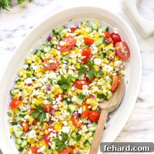 Overhead view of a vibrant corn salad bowl, garnished with fresh herbs.