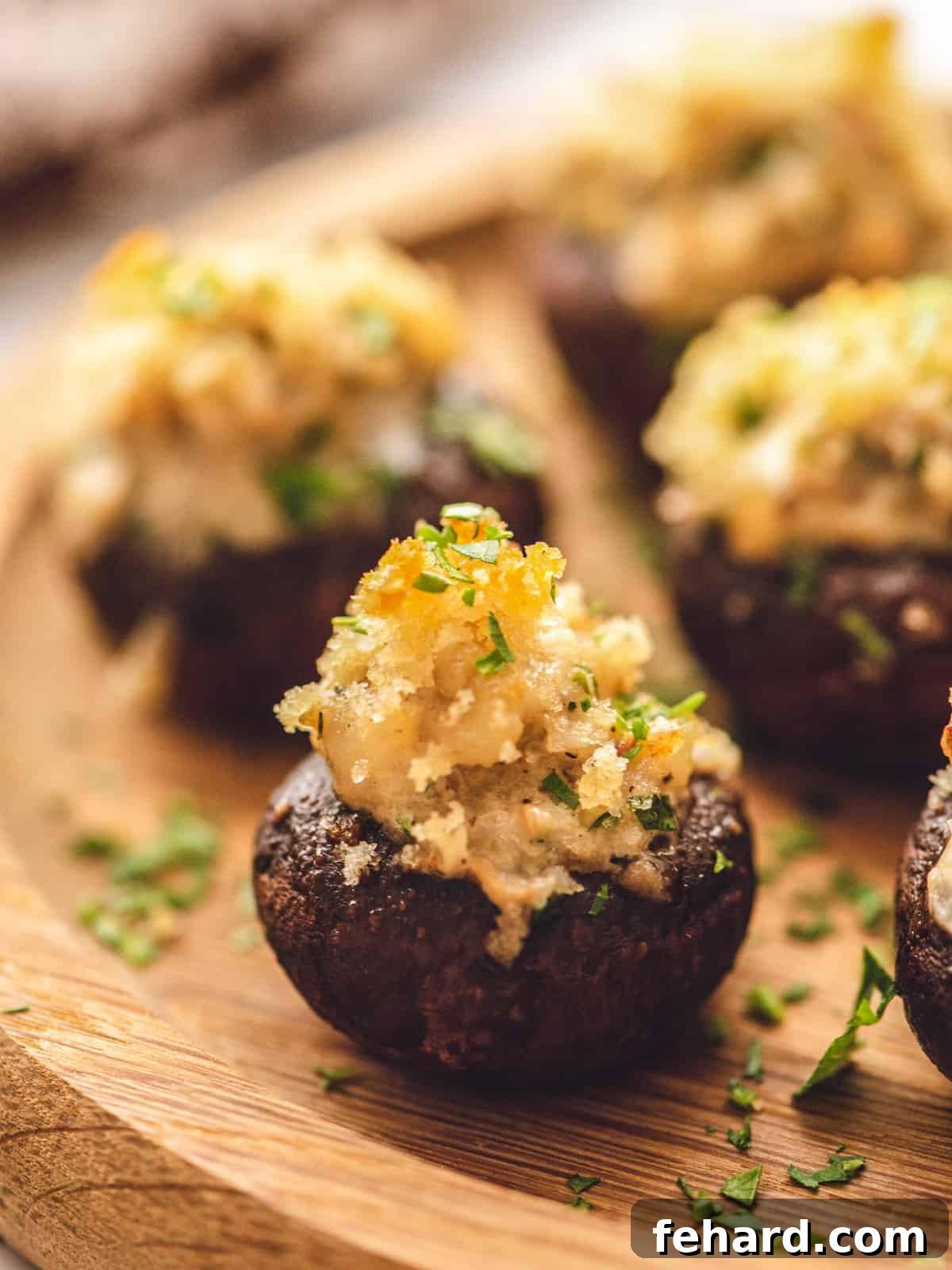 Best Sausage Stuffed Mushrooms for Parties Close up of a perfectly baked sausage stuffed mushroom, golden brown, on a rustic wooden platter.