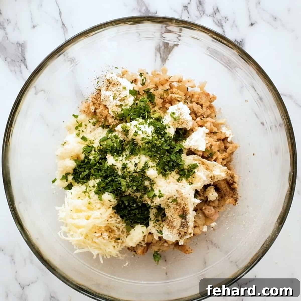 Cream Cheese Stuffed Mushroom Filling A glass bowl containing all the ingredients for the stuffed mushroom filling, including cooked sausage, softened cream cheese, and shredded cheeses.