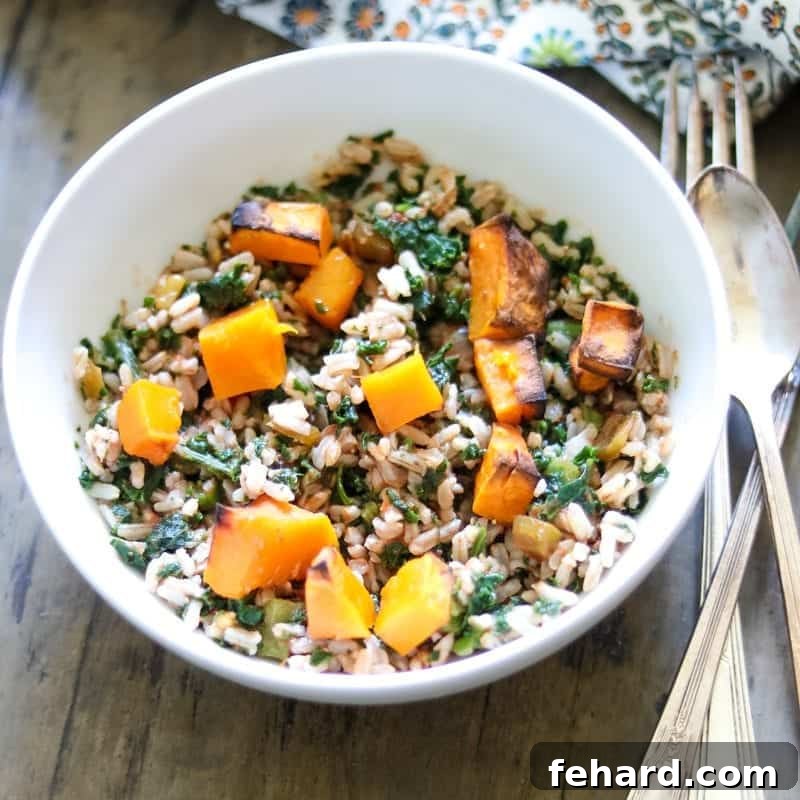 Brown rice, roasted butternut squash are tossed together with kale in white bowl