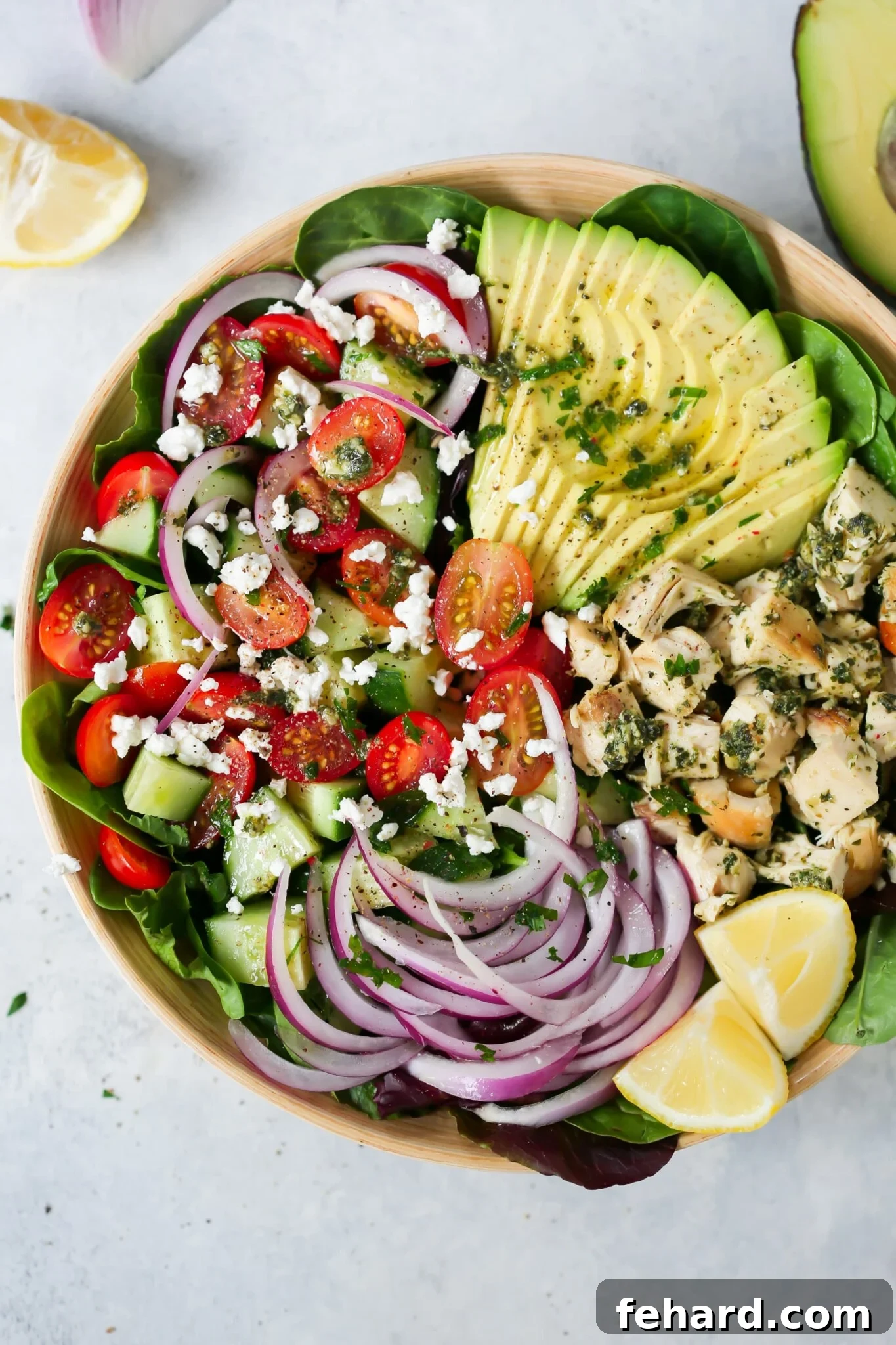Pesto Chicken Salad - This healthy, easy, filling and super delicious Pesto Chicken Salad recipe is loaded with lettuces, cherry tomatoes, avocado, red onions and flavoured with a light lemon dressing. A beautifully presented Pesto Chicken Salad in a large serving bowl, showcasing vibrant greens, red tomatoes, creamy avocado, and pesto-coated chicken pieces.