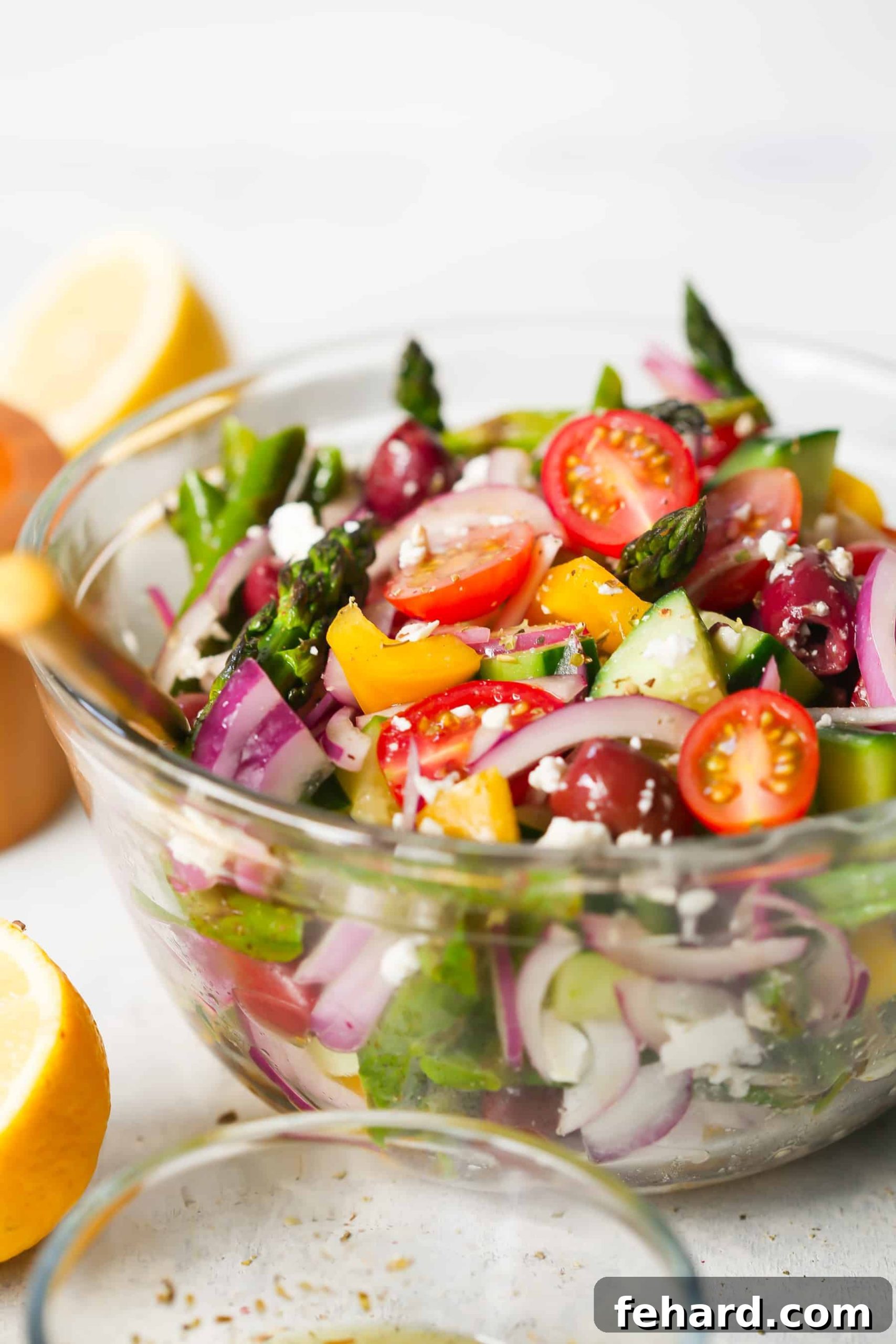 Asparagus Greek Chopped Salad - A close-up of the delicious lemon dressing being poured over the salad.