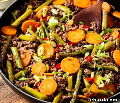 Close-up view of the finished ground beef with vegetables, garnished with green onions, ready to serve.