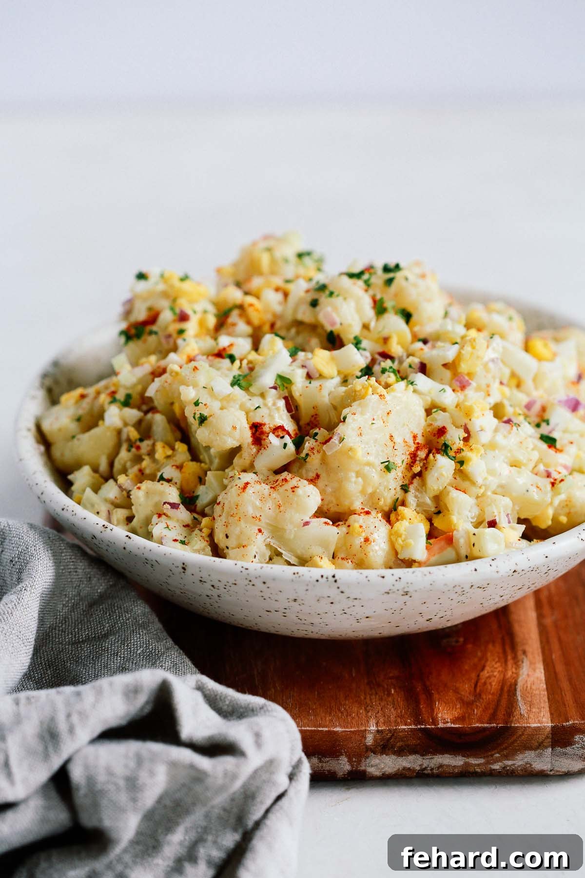 Low-Carb Cauliflower Potato Salad 3 cauliflower potato salad in a white bowl on a wooden board