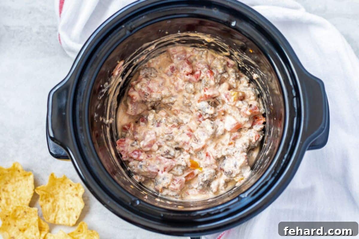 Cheesy sausage dip, creamy and melted, served warm in a slow cooker, ready for dipping.