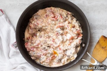Cream cheese, Rotel tomatoes, and sausage in a sauté pan.