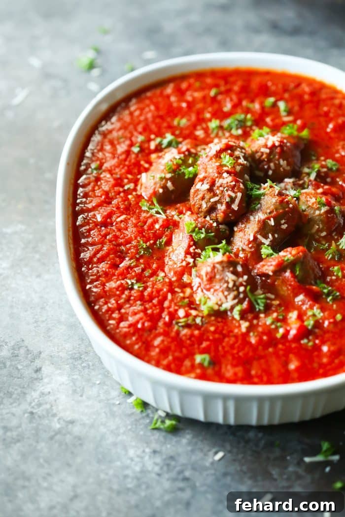Plated Italian Sausage Tomato Sauce served over pasta, garnished with fresh basil, ready to eat.
