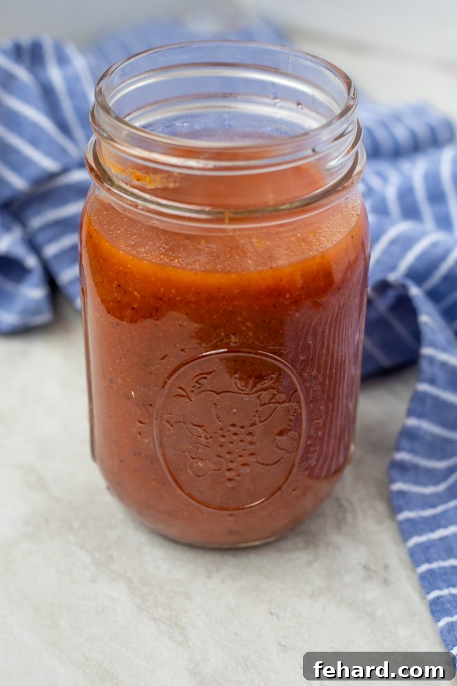 A glass jar filled with vibrant red homemade enchilada sauce, ready to be used or stored.