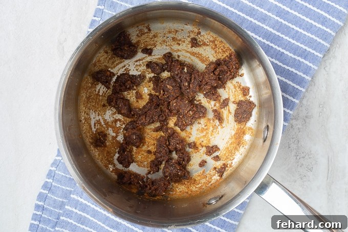 A saucepan on the stove with a golden-brown roux, the base for homemade enchilada sauce.