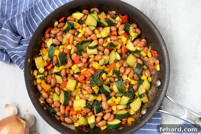 Skillet with vegetable mixture for vegan enchiladas.