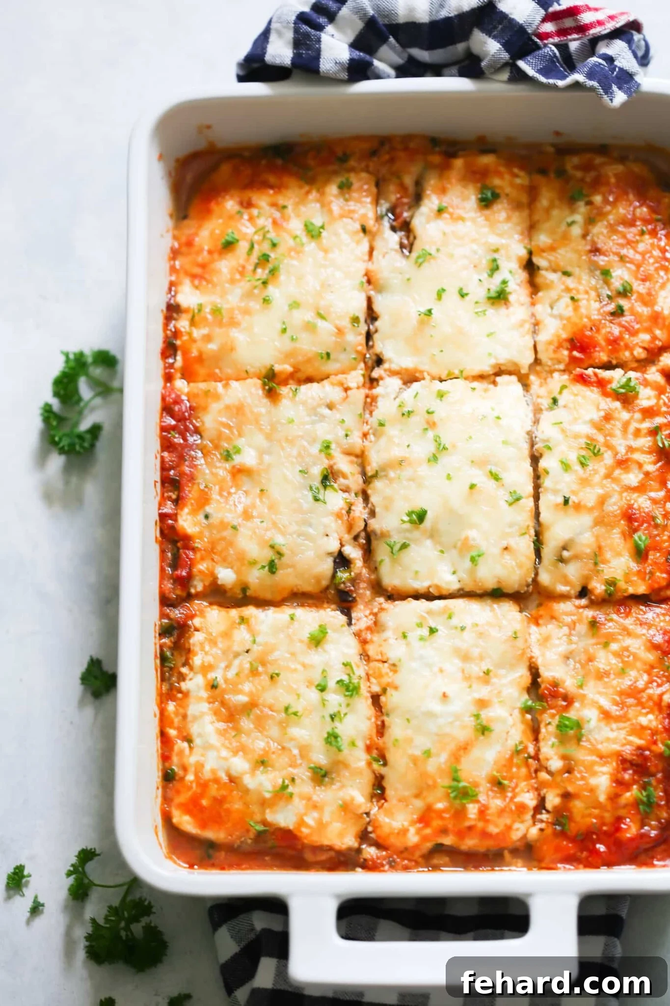 A beautifully presented low-carb eggplant lasagna in a large, white baking dish, fresh out of the oven, golden brown and bubbling.