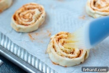 Brushing pizza rolls with infused olive oil. The prepared pinwheels are being brushed with the flavorful oil.