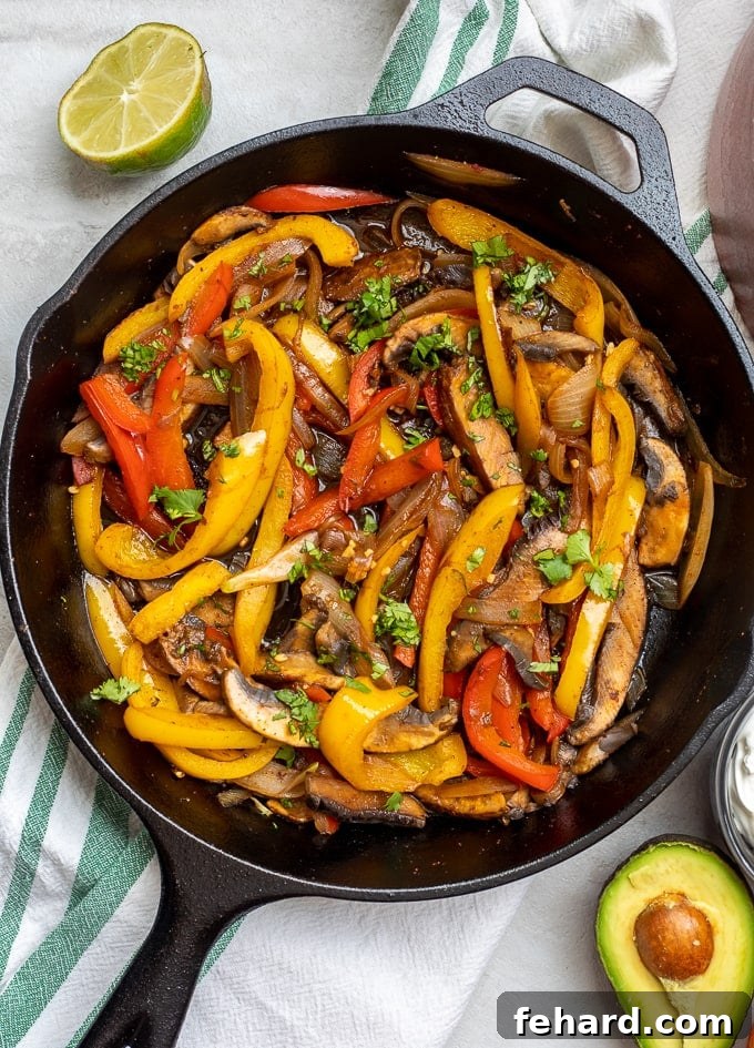 Cast iron skillet with vibrant veggie fajita mixture, loaded with colorful peppers, onions, and mushrooms.