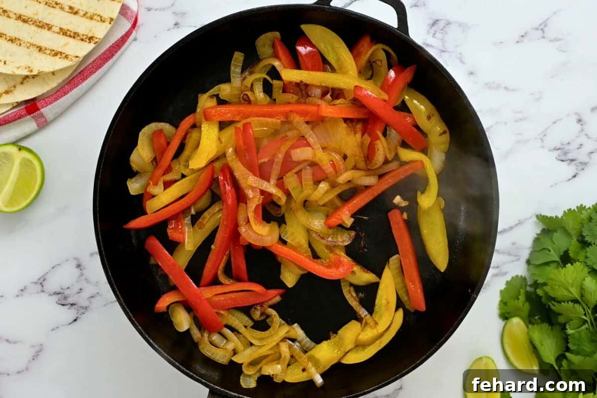 Yellow and red sweet bell peppers sauteed with onions in a cast iron skillet for the base of fajitas.