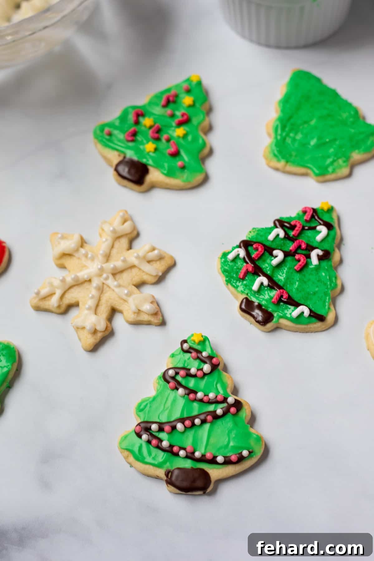 Perfectly Iced Sugar Cookies with Cream Cheese Frosting Beautifully decorated sugar cookies with green and white cream cheese icing and festive sprinkles, arranged on a white kitchen counter.