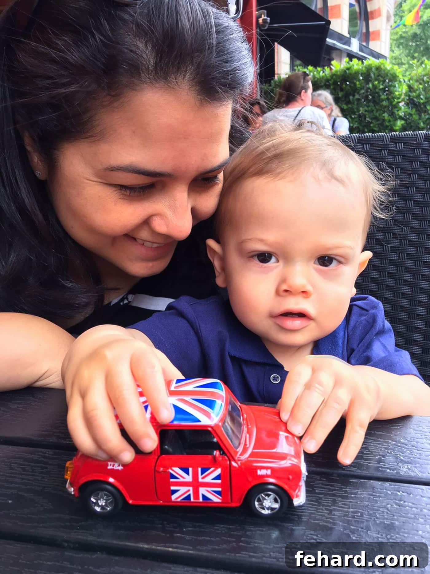 A mother and son playing with a red Mini Cooper car toy, a classic British symbol