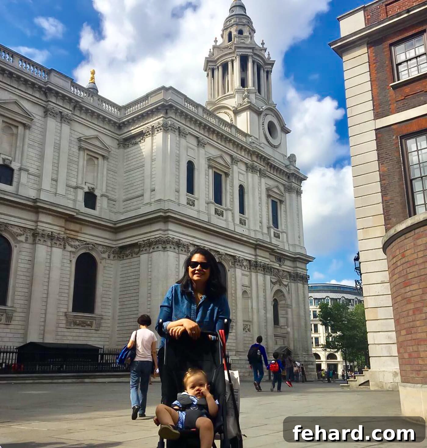 A mother gently pushing her toddler in a stroller through a London street