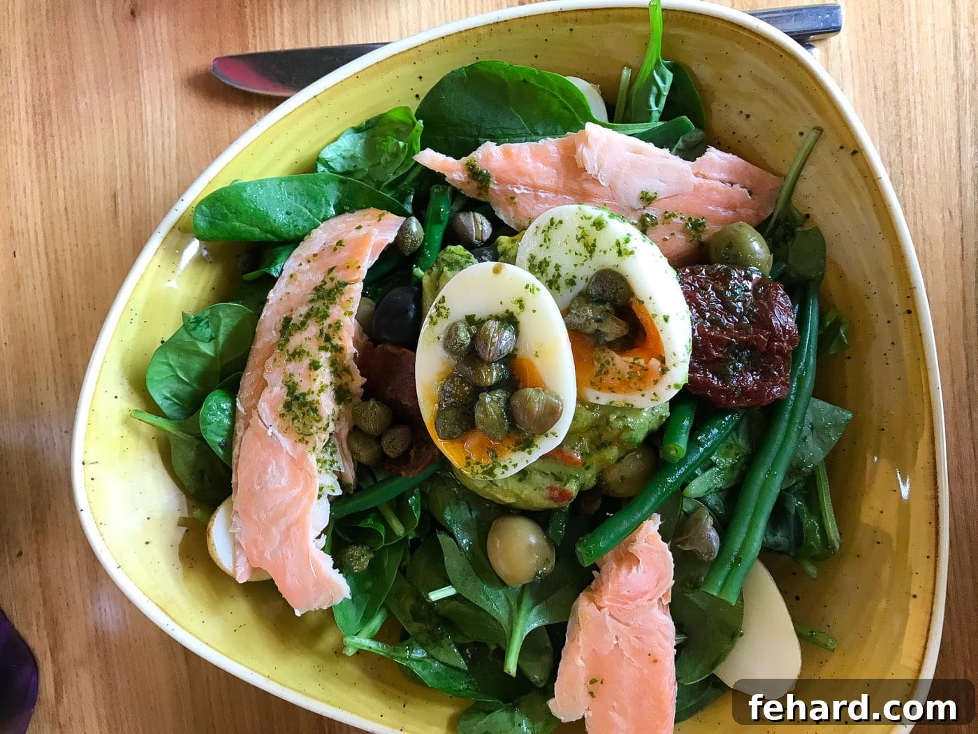An appealing overhead shot of a fresh salmon salad bowl on a rustic wooden table