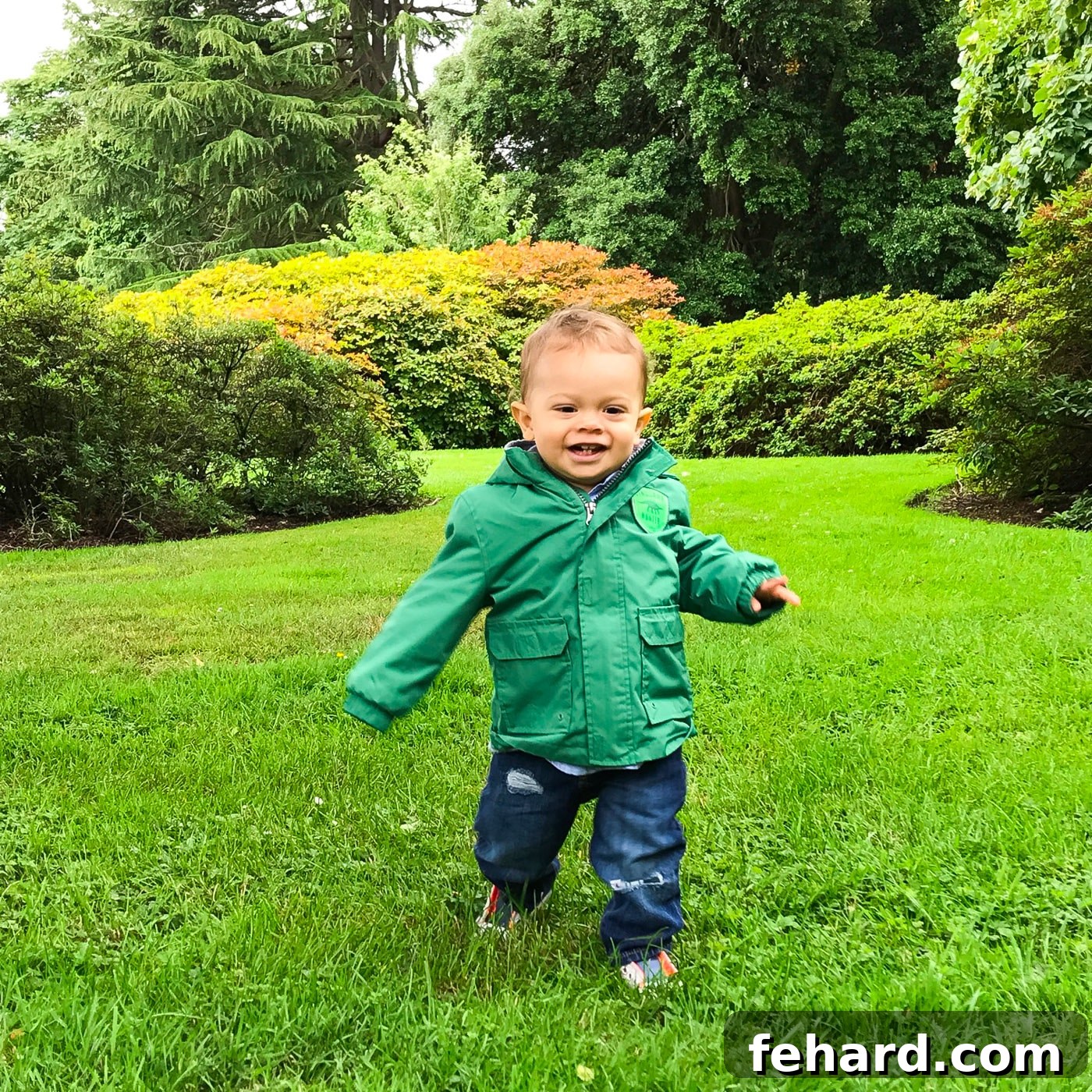 A joyful toddler running through a lush green park in Edinburgh