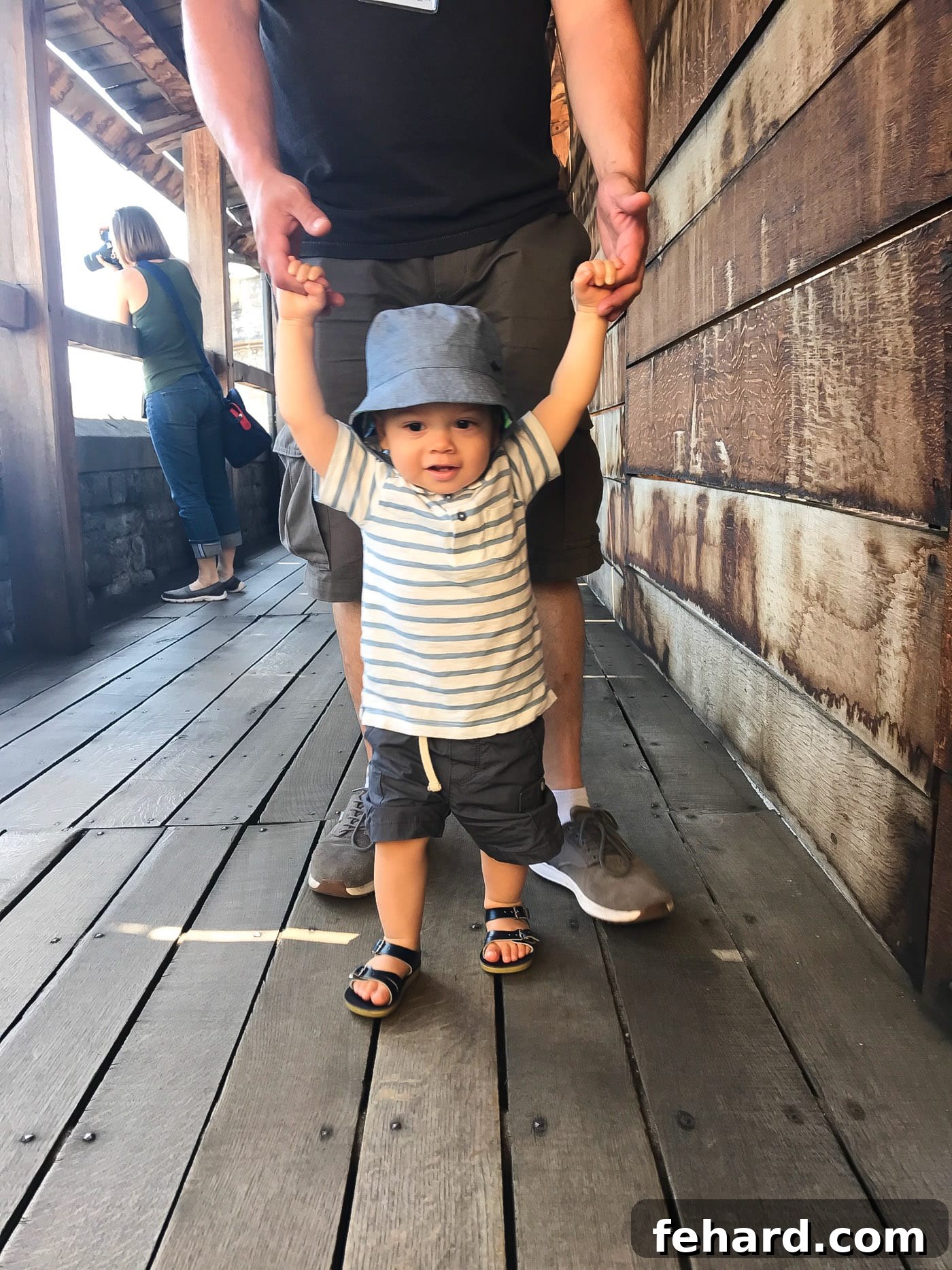 A heartwarming scene of a toddler walking hand-in-hand with his father through a London park