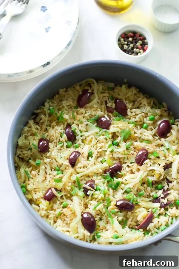 A beautifully presented bowl of Leek Kalamata Rice, topped with fresh green onions and whole Kalamata olives, ready to serve.