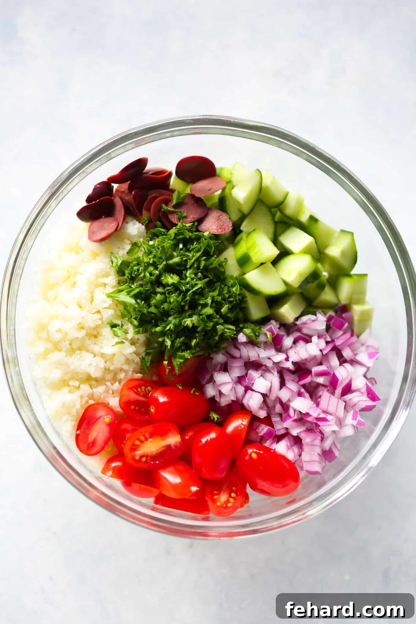 Close-up of a refreshing Mediterranean Cauliflower Salad, featuring a medley of colorful veggies and riced cauliflower. Perfect for a healthy, plant-based meal.
