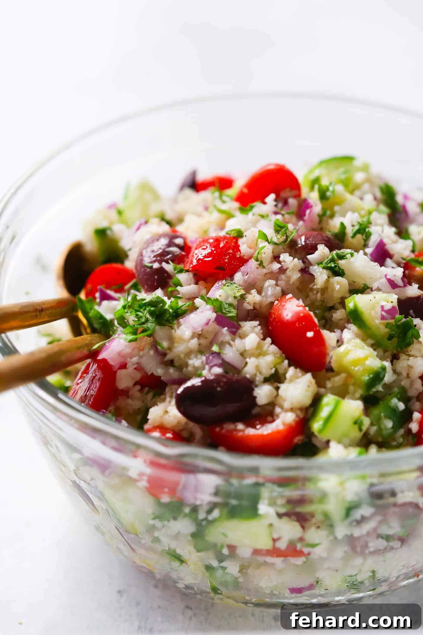 A bowl of Mediterranean Cauliflower Salad served on a rustic wooden table, emphasizing its fresh, wholesome ingredients. A fantastic vegan and gluten-free option.