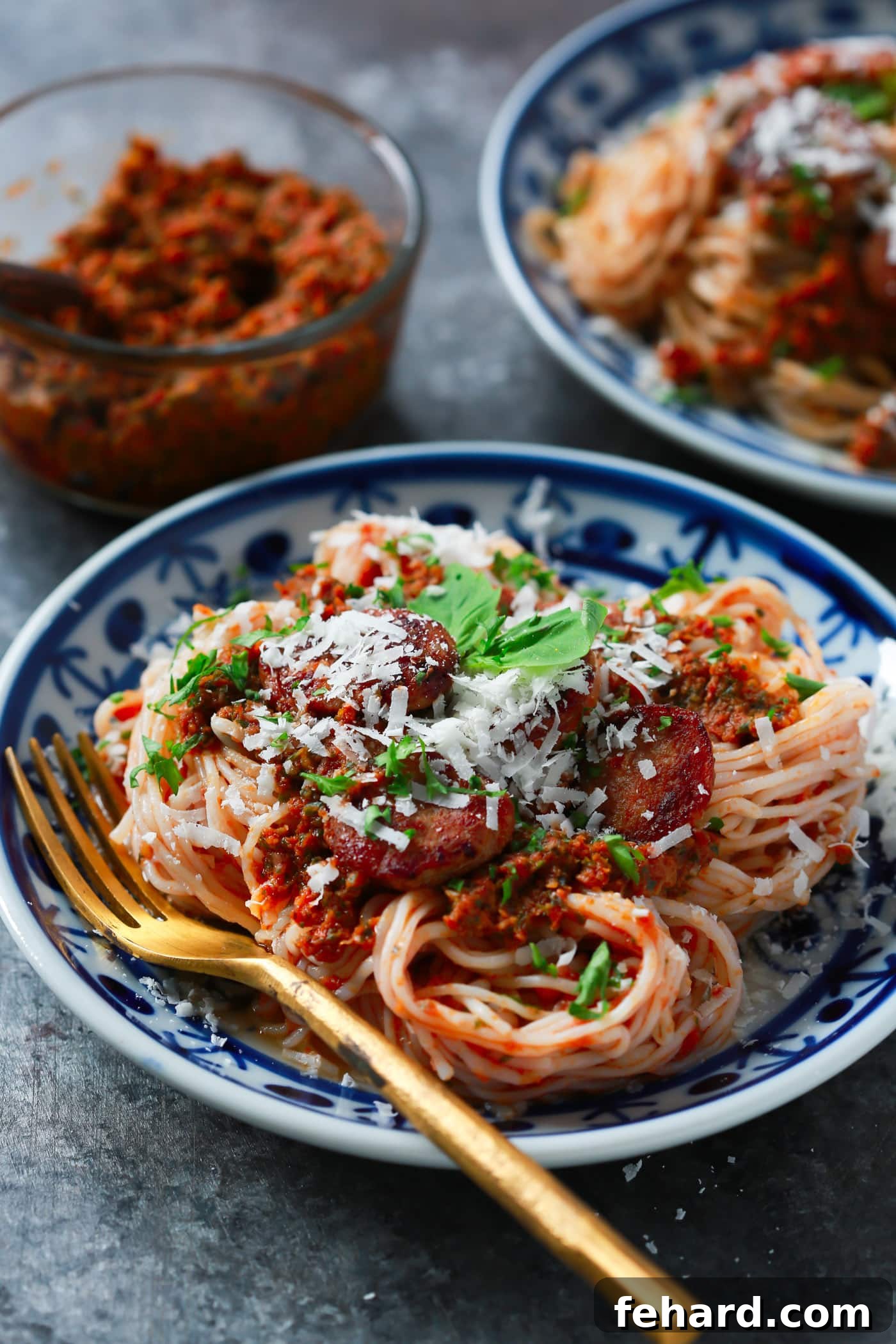 Low-Carb Italian Sausage Sun-Dried Tomato Pesto Pasta A close-up shot of Italian Sausage Sun-dried Tomato Pesto Pasta, showcasing the rich red pesto, savory sausage, and slender pasta strands, all looking incredibly flavorful and inviting. Ideal for a low-carb and gluten-free diet.